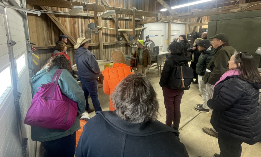 People standing in a semi-circle listening to someone speak in a garage